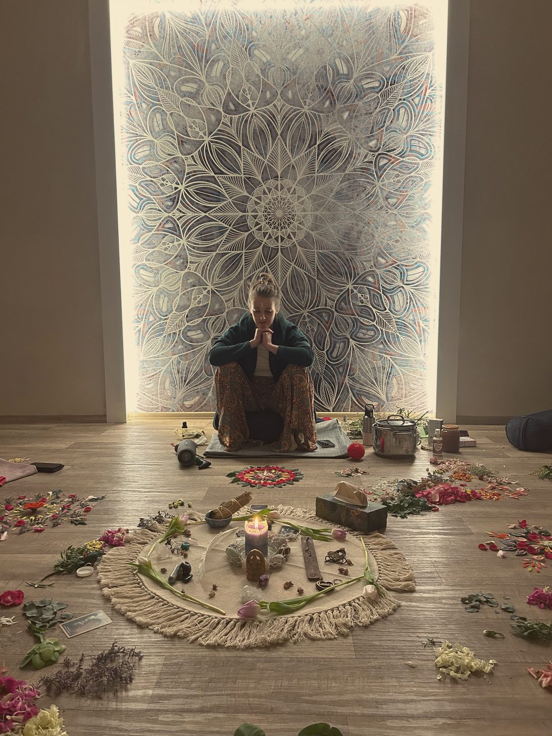 Žena v meditaci u oltáře před velkou mandalou